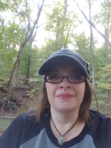 It's me, in the woods, wearing a cap and the mildly creepy eye necklace I break out every year at Halloween.